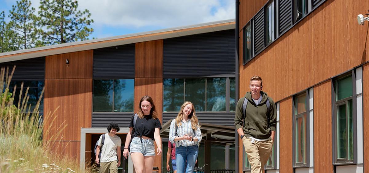 Students walk on the sidewalk outside a building at OSU-Cascades. 
