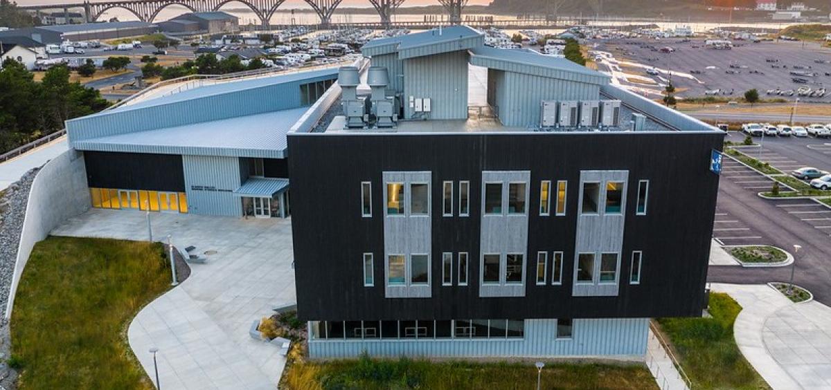Image of an aerial view of the Gladys Valley Marine Studies Building with the Yaquina Bay Bridge in the background. 