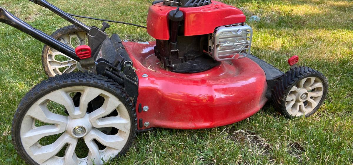 A red lawn mower sitting on fresh cut green grass.