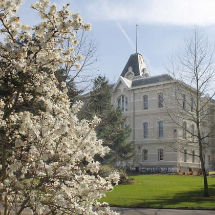 Image of Community Hall on Oregon State Campus with spring flowering tree in foreground 