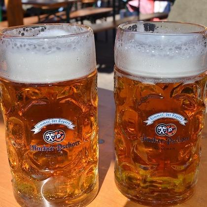 Image shows two full glass steins of beer with a foamy top 