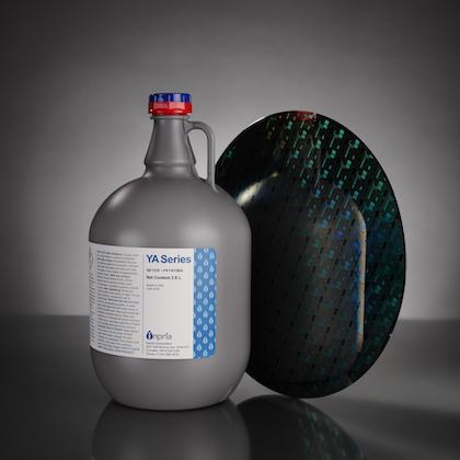 Image of a large gray jug with a sample of the dark, reflective material next to it