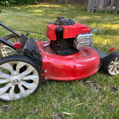 A red lawn mower sitting on fresh cut green grass.