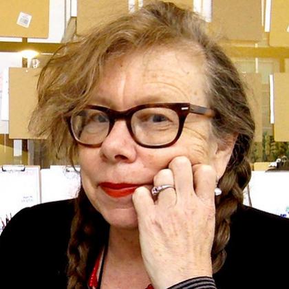 Headshot of Lynda Barry, wearing glasses, red lipstick & hair in two braids.
