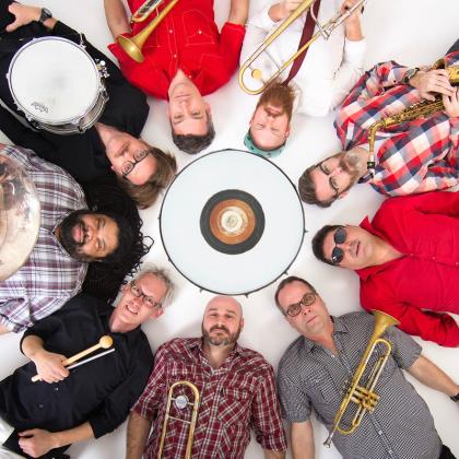 Image of the 9 members of Slavic Soul Party! lying in a circle
