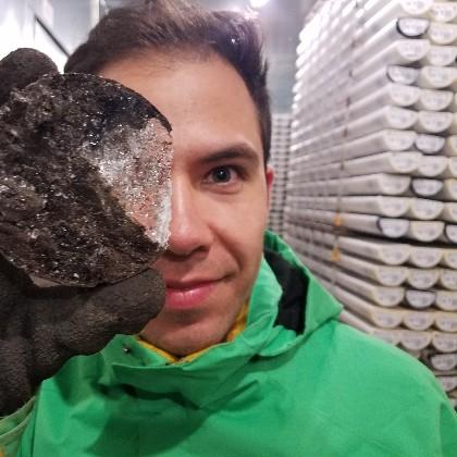 Adrian Gallo holds a disc of ice from a permafrost core in the OSU corelab freezer.