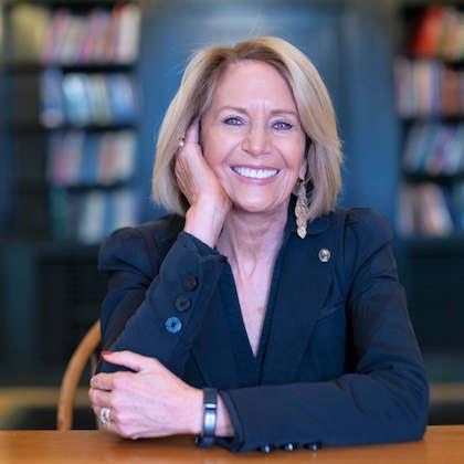Headshot of Marcia McNutt, president of the National Academy of Sciences. She has short blonde hair and is wearing a dark blue blazer, seated with her elbows propped on a table and one hand supporting her chin as she looks at the camera.